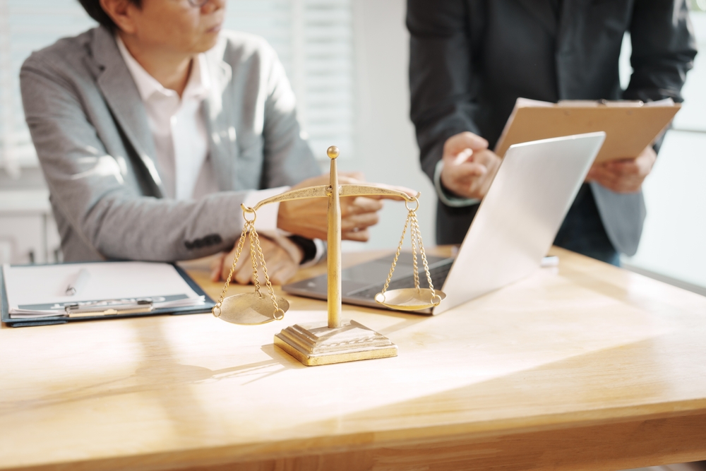 Legal professionals reviewing documents in an office with scales of justice in the foreground, representing immigration suitability assessments and legal decision-making.